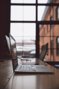 Opengeklapte laptop op een houten tafel voor een groot raam